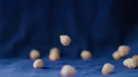 A-rain-of-chickpeas-falls-in-slow-motion-against-an-electric-blue-background