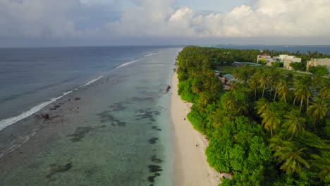 Luftaufnahme-Der-Ruhigen-Küste-Einer-Maledivischen-Insel-Bei-Sonnenaufgang,-Während-Türkisfarbene-Wasserwellen-Sanft-Am-Ufer-Brechen