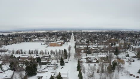Aerial-view-tracking-backwards-over-an-empty-road-in-a-snowy-Manitoba-town