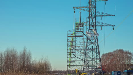 Linemen-running-lines-on-a-newly-erected-powerline-tower-pylons-with-the-help-of-a-crane---time-lapse