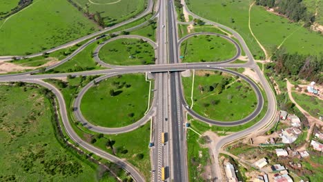 Dolly-in-aerial-view-of-a-traffic-circle-in-the-middle-of-a-meadow-full-of-green-grass