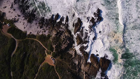 High-angle-top-down-view-of-turbulent-waves-crashing-against-rocky-coastline