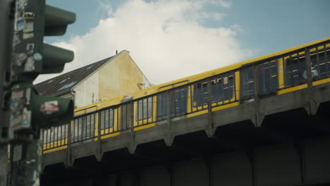Yellow-U-Bahn-Train-Passing-over-an-Industrial-Bridge-in-Berlin,-Germany