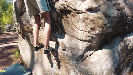Young-man's-lower-half-in-climbing-shoes-tiptoeing-climb-over-small-edge-boulder