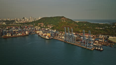 Panama-City-Aerial-V47-Filmische-Kamerafahrt-Mit-Frachtschiff-Und-Autotransporter,-Die-Am-Hafen-Von-Port-Balboa-Angedockt-Sind,-Mit-Ancon-Hill-Und-Stadtbildhintergrund---Aufgenommen-Mit-Mavic-3-Cine---März-2022