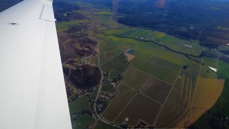 POV-shot-from-a-plane-window,-overlooking-rural-fields-and-highlands-of-California,-USA