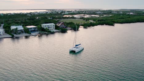 Aerial,-a-sailboat-anchored-off-the-coast-at-sunset,-Florida-Keys