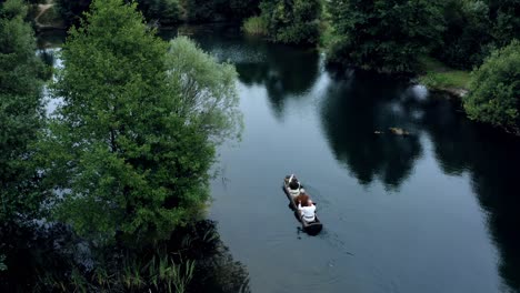 Drone-tracking-couple-of-men-boating-in-dugot-wooden-boat-on-dark-water-river