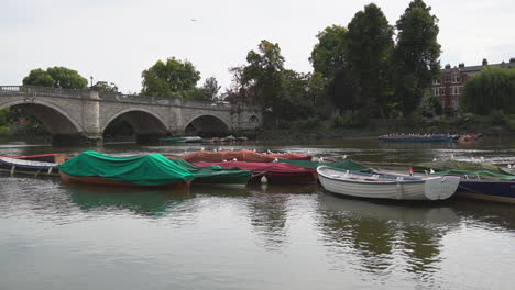 River-Thames-flows-past-stone-arch-bridge-in-London-suburb,-Richmond