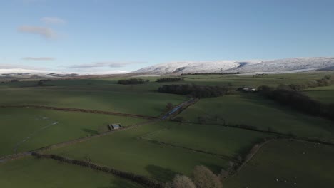 Verdant-green-farmland-in-Lancaster-UK,-with-snow-dusted-hills-beyond