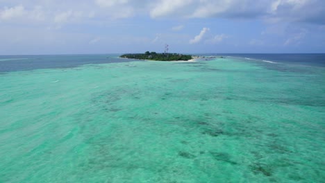 Drone-flying-over-turquoise-seawater-towards-Dhangeti-tropical-and-local-island,-Maldives