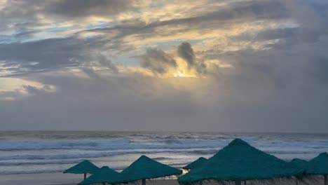 Wellen,-Die-An-Einem-Strand-Mit-Erstaunlichem-Sonnenuntergang-Mit-Einigen-Leeren-Blauen-Strohhalmen-Brechen