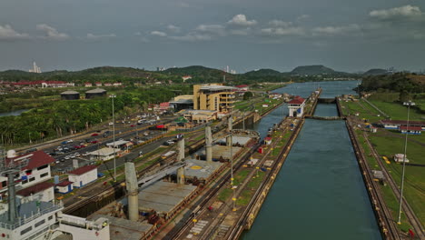 Panama-City-Aerial-v33-low-flyover-miraflores-locks-mechanism-capturing-details-of-cargo-tanker-ship-transiting-at-the-station-across-the-narrow-canal-waterway---Shot-with-Mavic-3-Cine---March-2022