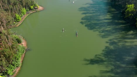 Aerial-view-dolly-in-of-the-Curauma-lagoon,-with-rowing-teams-practicing-and-passing-each-other,-Chile