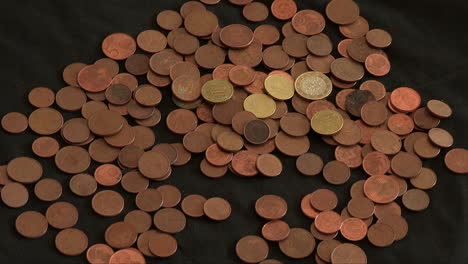 A-hand-pulling-out-1-euro-and-cent-coins-that-are-placed-on-a-dark-cloth