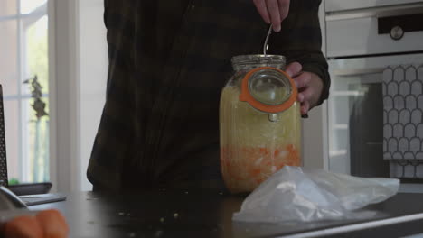 Closeup-of-man-inserting-freshly-vegetables-inside-jar-for-fermentation-process