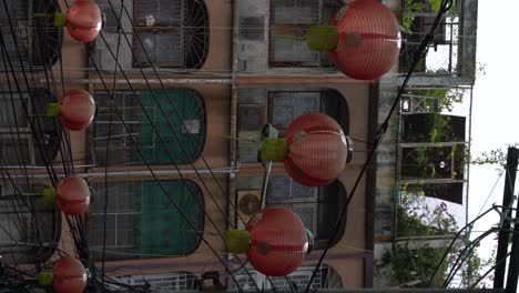 Vertical-video---Red-lanterns-blow-by-wind-and-adorn-a-small-alley-in-Chinatown-Bangkok,-Thailand