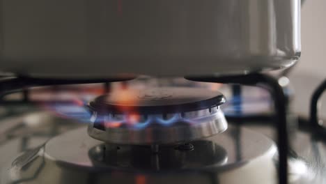 Natural-gas-stove-blue-flames-under-stainless-steel-cooking-pot,-close-up