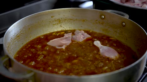 Raw-Chicken-Poultry-Pieces-Being-Placed-And-Cooked-In-Simmering-Curry-Sauce-In-Pot