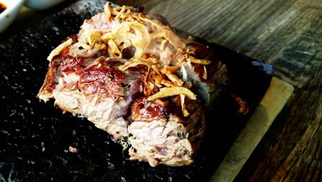 Japanisches-Steak-In-Nahaufnahme,-Das-Auf-Einem-Lavafelsen-Um-180-Grad-Geschwenkt-Wird,-Während-Das-Bio-Kobe-Fleisch-Selbst-Kocht-Und-Mit-Dampfenden-Zwiebeln-Belegt-Wird