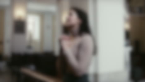 Blurred-shot-of-woman-praying-in-front-of-an-altar-with-folded-hands-in-a-catholic-church