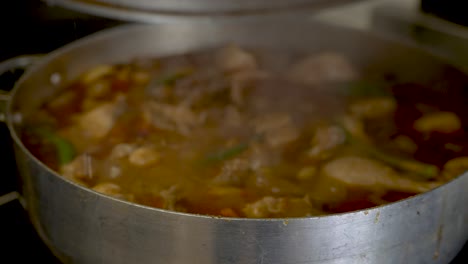 Lid-Being-Lifted-Off-Large-Cooking-Pot-With-Steam-From-Simmering-Chicken-Curry-Escaping