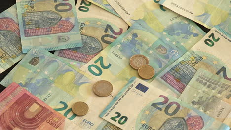 Image-of-20-and-10-Euro-banknotes,-with-several-coins-falling-on-the-banknotes