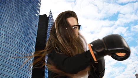 Sexy-beautiful-businesswoman-fight-against-stress-due-to-work-by-wearing-boxing-gloves-and-punching-toward-camera-with-skyscrapers-in-background