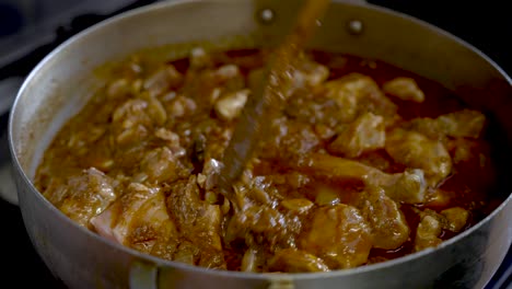 Chicken-Pieces-Being-Stirred-In-Simmering-Rich-Curry-Sauce-Inside-Large-Pot