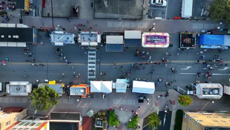 Top-down-aerial-of-people-enjoying-town-fair-on-street