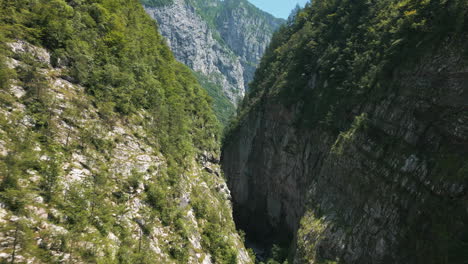 Drone-video-flying-under-mountain-road-bridge-panning-up-slowly-to-reveal-deep-chasm-valley-in-the-Italian-Dolomites-surrounded-by-mountains-roads-and-cliffs