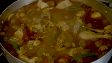 Close-Up-View-Of-Bubbling-Simmering-Chicken-Curry-With-Fresh-Green-Chillies