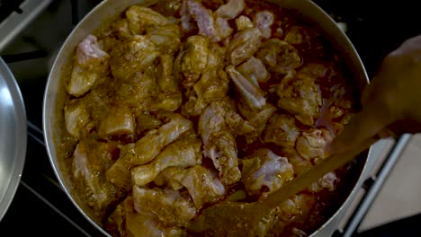 Birds-Eye-View-Of-Chicken-Pieces-Being-Stirred-In-Rich-Curry-Inside-Large-Pot