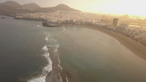 Fantastic-aerial-shot-of-development-and-at-dawn,-showing-the-natural-barrier-of-the-beach-and-also-showing-the-wonderful-beach-of-Las-Canteras-and-the-buildings-in-the-area
