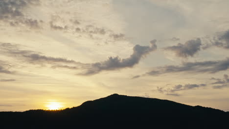 Static-Shot-Of-A-Sun-Setting-Behind-A-Large-Silhouetted-Hill