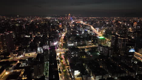 Aerial-hyperlapse-shot-over-Taipei-towers,-101-Tower-and-traffic-on-roads-at-night---Glowing-digital-lines-connecting-modern-network-city-in-Asia