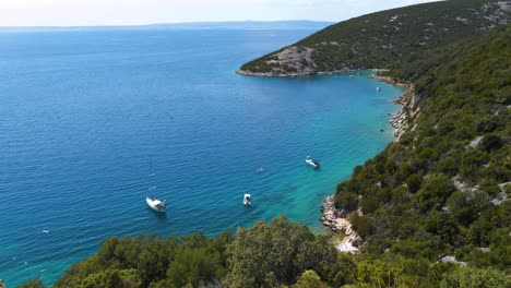 Aerial-view-of-a-spectacular-beach-in-Croatia-deep-blue-sea-over-green-vegetation-and-white-sand