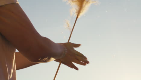 Close-up-Shot-Of-A-Young-Woman-Spinning-Pampas-Grass-In-Her-Hands-Under-The-Sunlight