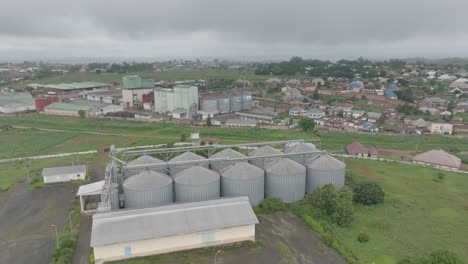 AERIAL---Grain-silos-and-town,-Jos-Plateau,-Nigeria,-rising-shot