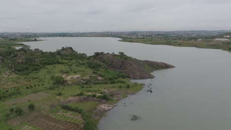 AERIAL---Lamingo-Dam-on-a-cloudy-day,-Jos-Plateau,-Nigeria,-forward-shot