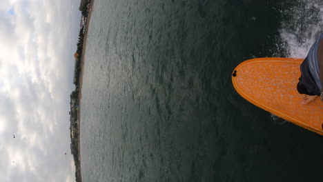 Young-man-surfing-on-orange-board,-POV-vertical-video
