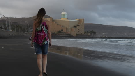 Fantastic-sunset-shot-of-a-woman-walking-along-Las-Canteras-beach-and-seeing-the-Alfredo-Kraus-Auditorium-in-the-background