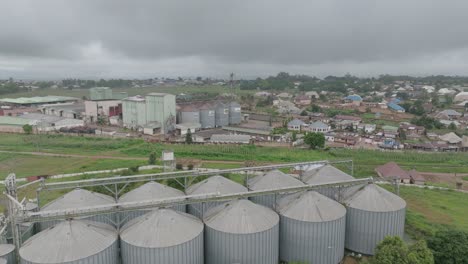 AERIAL---Grain-silos-and-town,-Jos-Plateau,-Nigeria,-forward-shot