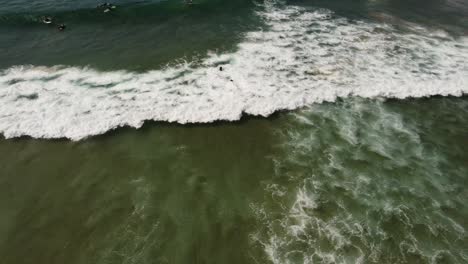 Man-surfing-waves-in-the-beach-aerial-view