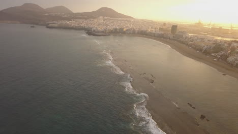 Fantastic-aerial-shot-at-dawn,-showing-the-natural-barrier-of-the-beach-and-also-showing-the-wonderful-beach-of-Las-Canteras-and-the-buildings-in-the-area