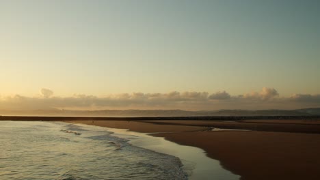 Scenic-view-of-beach-and-mountains-in-the-sunset-at-Costa-da-Caparica,-Portugal