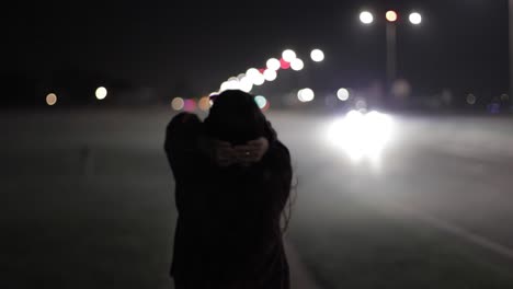 Young-Woman-Walking-Through-The-Streets-At-Night-Clutching-Her-Hands-Behind-Her-Head