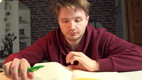 A-young-graduate-student-flips-through-his-notebook,-jotting-down-ideas,-and-is-annotating-and-expanding-notes-for-a-software-engineering-class