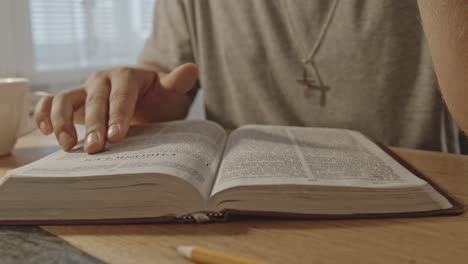 Close-up-of-Christian-man-carefully-reading-the-bible,-moving-fingers-along-the-text-lines