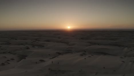 Sunset-on-Horizon-while-People-Explore-Baja-California-Sur-Sand-Dunes,-Aerial